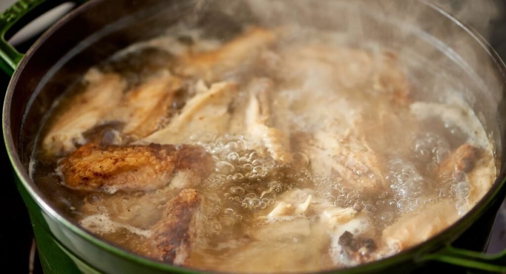 "Pot of chicken stock simmering on the stove with vegetables and herbs"