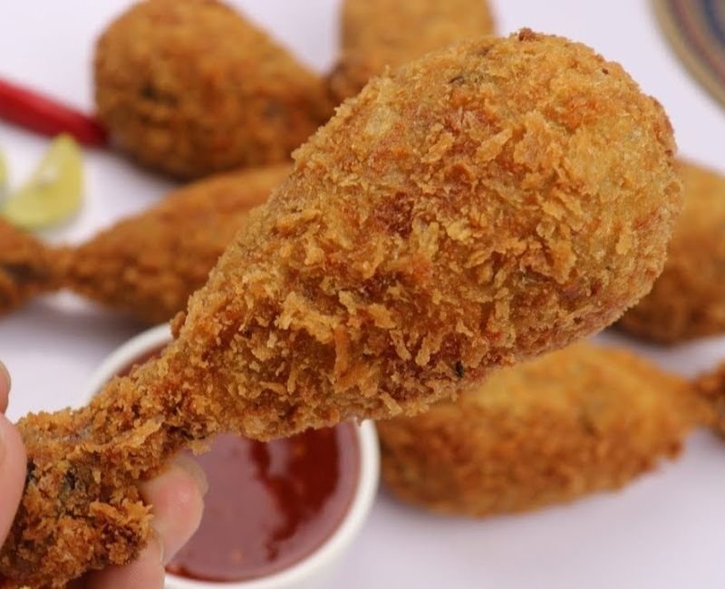“Close up of fried chicken drumstick showing crispy coating and juicy tender meat inside”